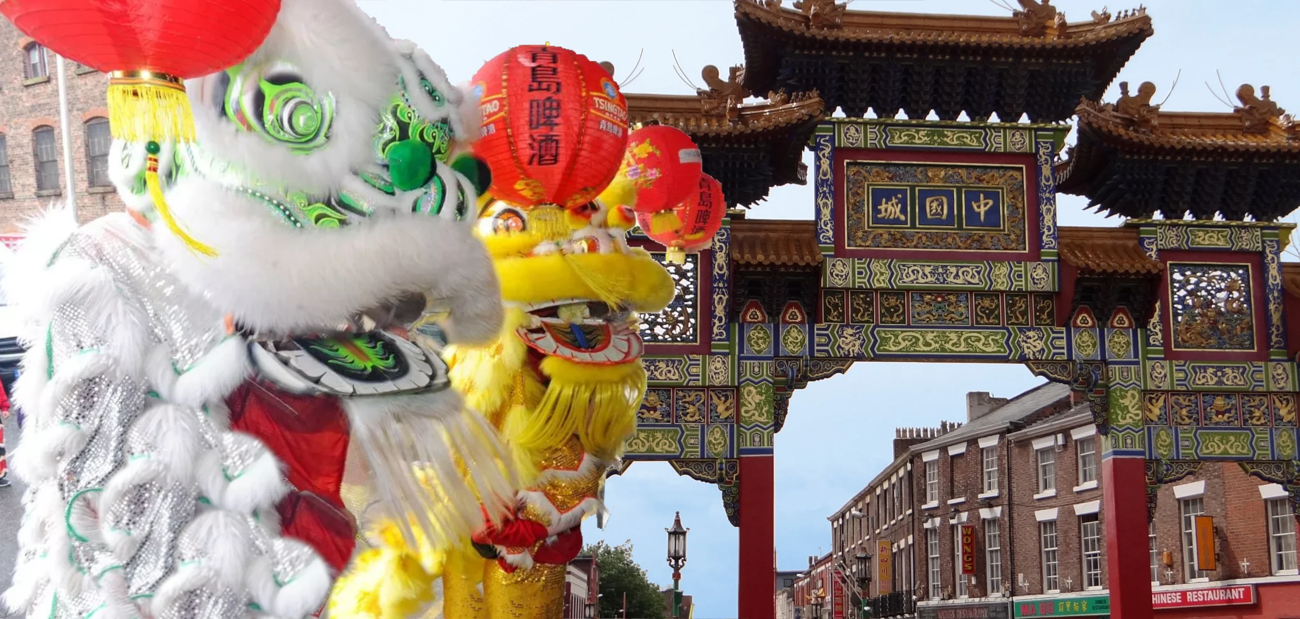 Two costumed lion dancers, one white and one yellow, perform in front of the ornate Liverpool Chinese Arch on Nelson Street, which is adorned with traditional red lanterns.