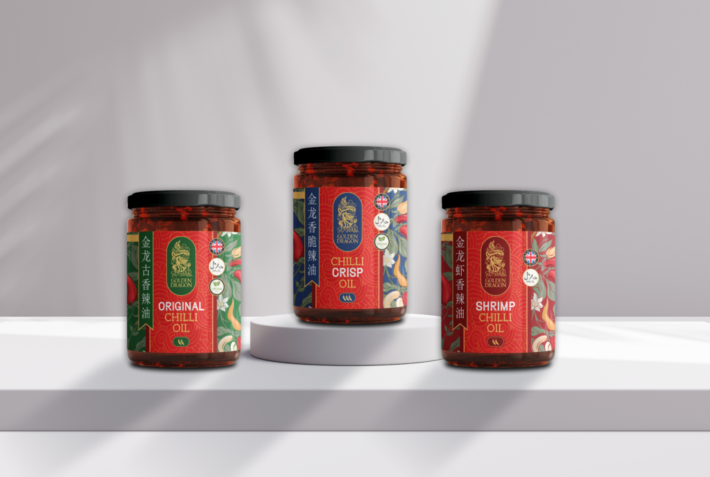 Three glass jars of Golden Dragon brand chilli oil—Original, Chilli Crisp, and Shrimp—arranged on a white pedestal against a minimalist grey background.