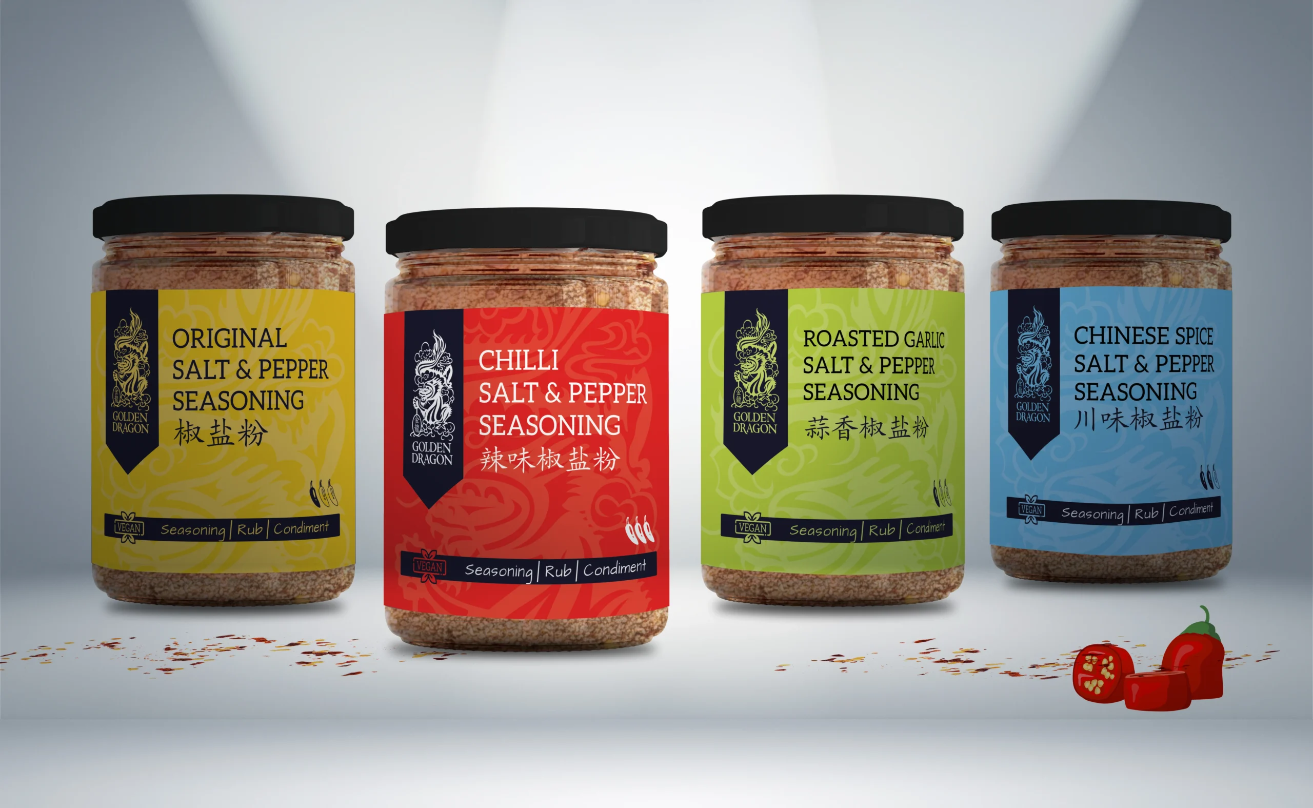 Four clear glass jars of Golden Dragon Salt and Pepper Seasoning—Original, Chilli, Roasted Garlic, and Chinese Spice—displayed in a row on a white surface with scattered spices and red chillies.